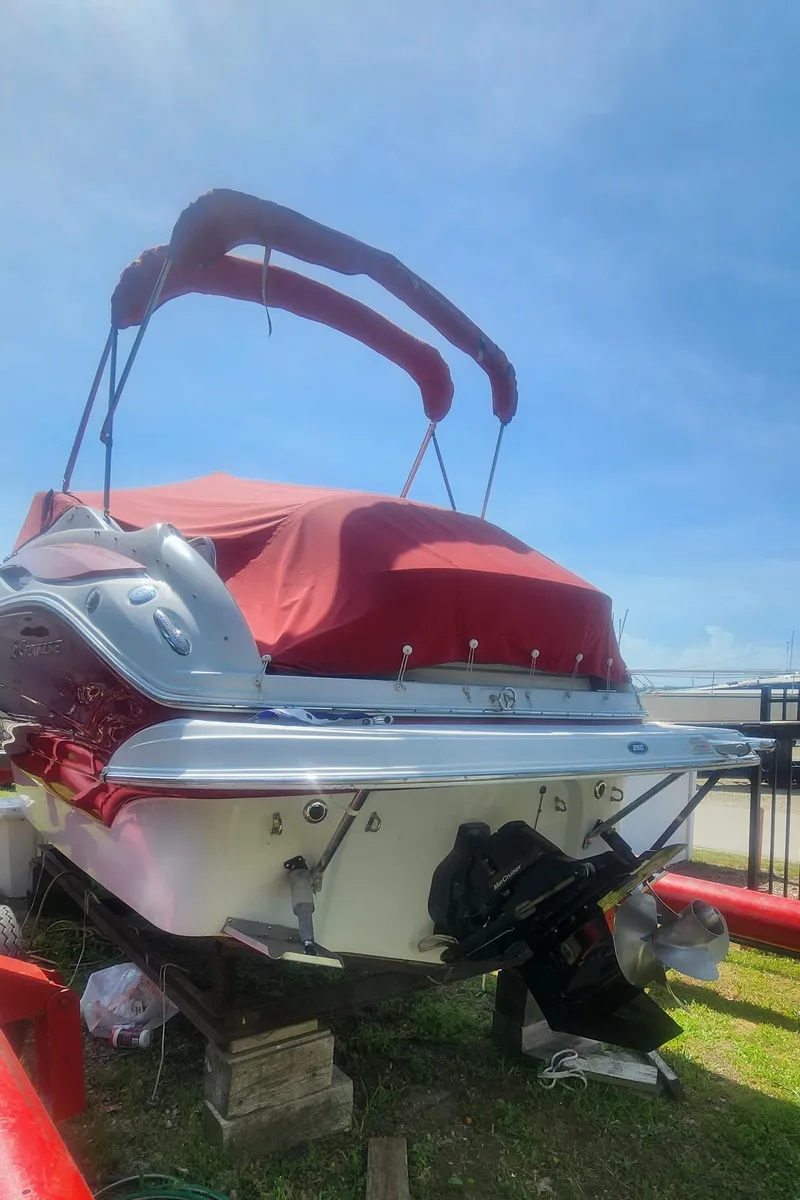 Slide: The Image of 2009 Crownline 250cr boat with red cover, docked on land under a clear blue sky. - 31
