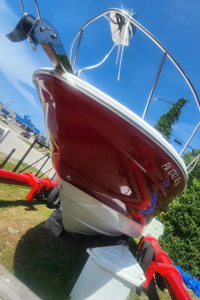 Slide: The Image of 2009 Crownline 250cr boat on trailer, red hull, parked outdoors under blue sky. - 4