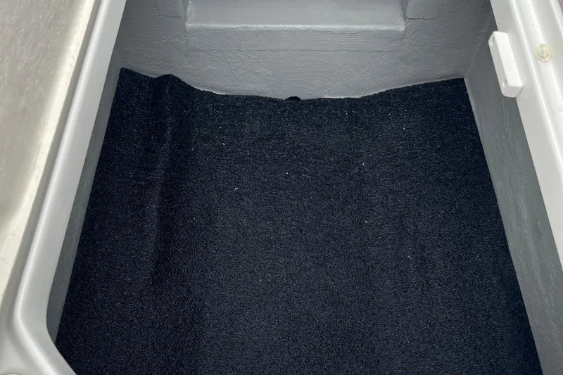 Slide: The Image of Storage compartment in 2026 Crownline 270 SS boat, featuring black carpeted interior. - 23