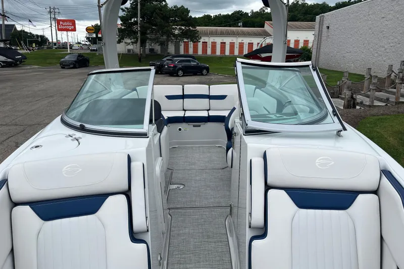 Slide: The Image of 2026 Crownline 270 SS boat interior with white and blue seating, parked outdoors. - 8