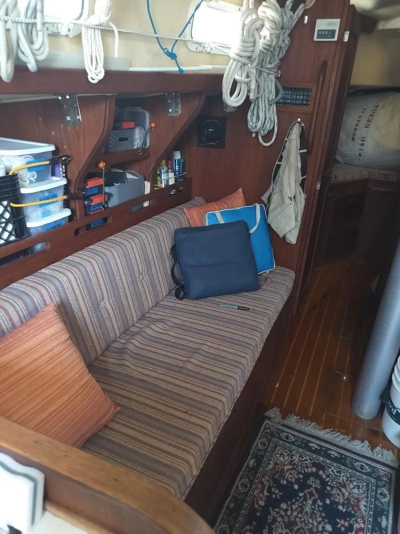 Slide: The Image of Interior of a 1983 Morgan 32-3 sailboat with striped seating and organized storage. - 15