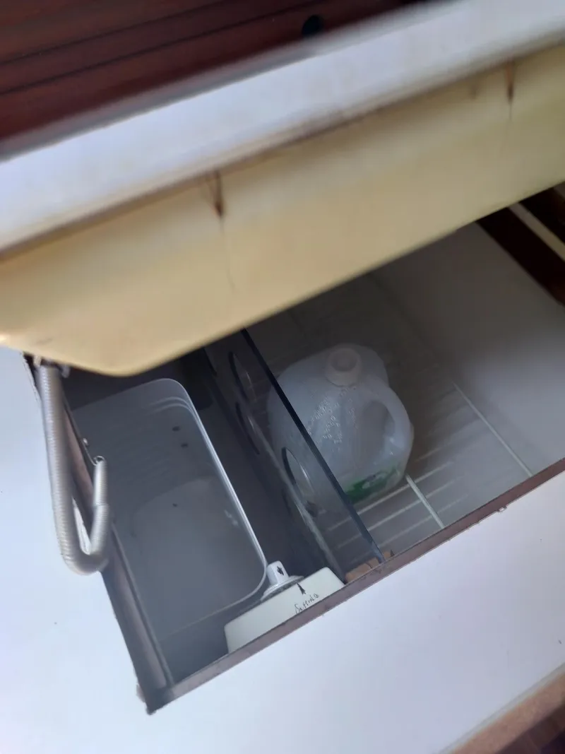 Slide: The Image of Open storage compartment in 1983 Morgan 32-3, containing a water jug and empty container. - 22