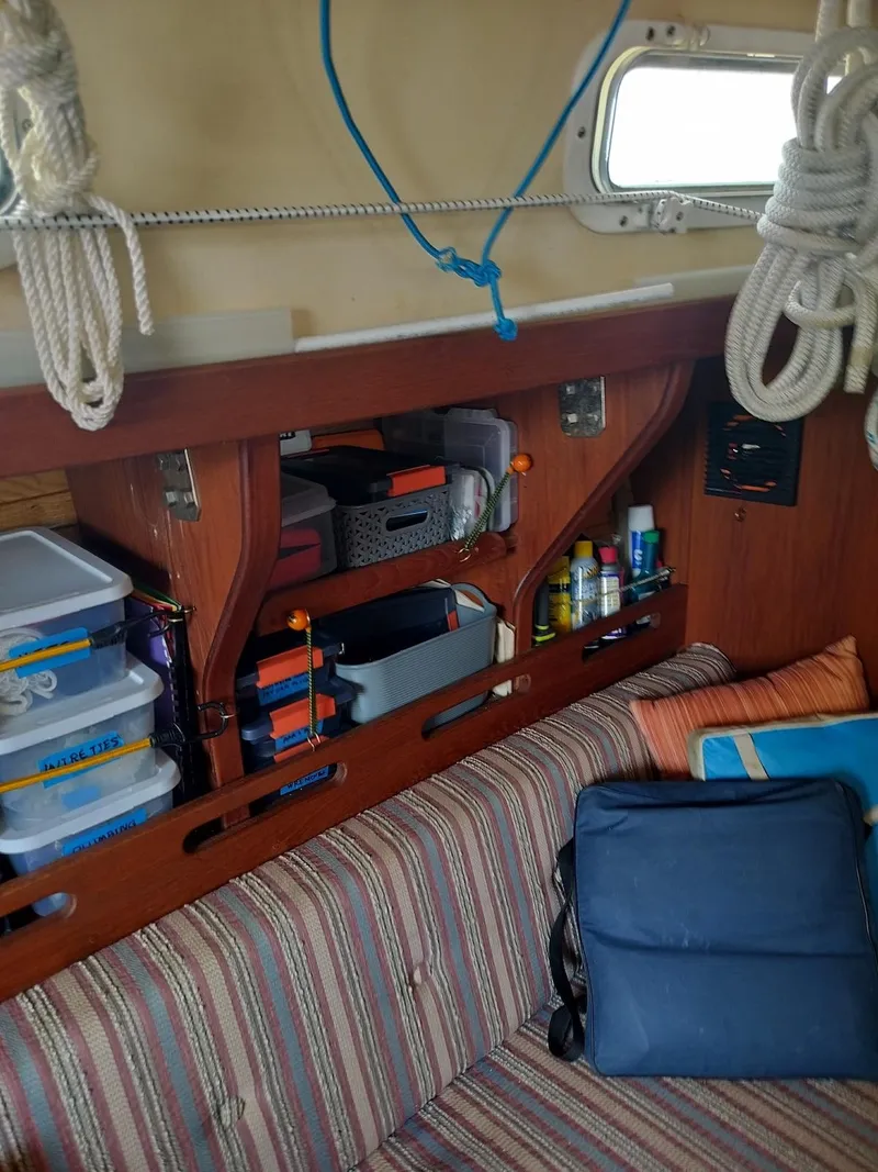 Slide: The Image of Interior of a 1983 Morgan 32-3 sailboat with organized storage and striped seating. - 9