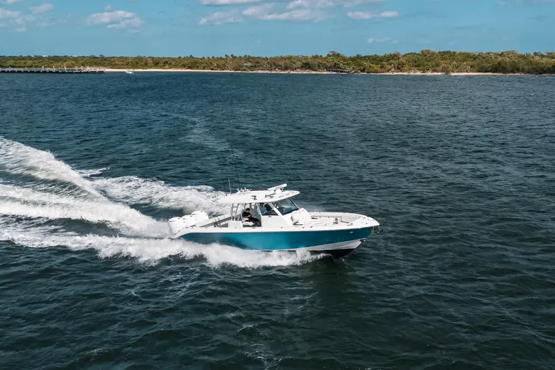 Slide: The Image of 2022 Everglades 395cc boat cruising on open water near a distant shoreline. - 10