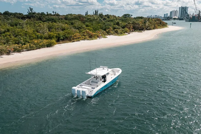 Slide: The Image of 2022 Everglades 395cc boat cruising near a scenic shoreline with lush greenery. - 14