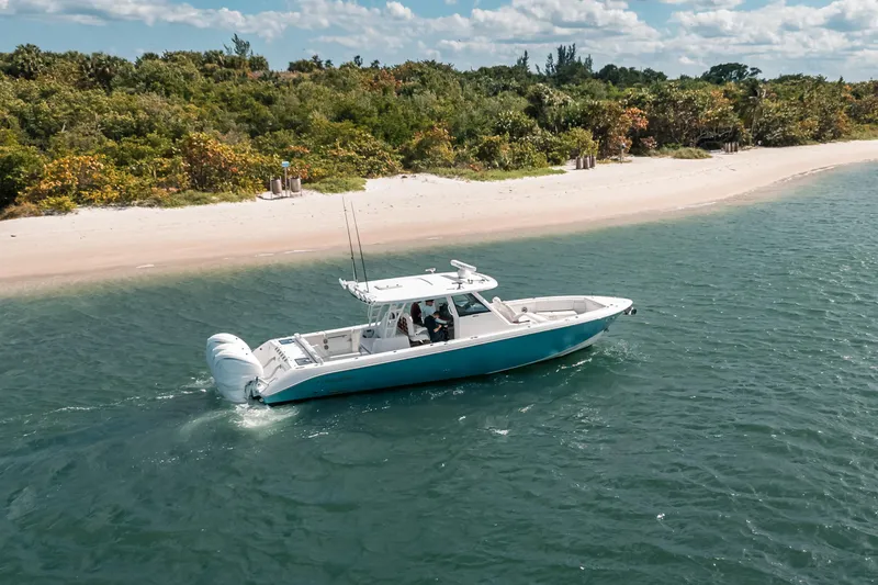 Slide: The Image of 2022 Everglades 395cc boat cruising near a sandy beach with lush greenery. - 15