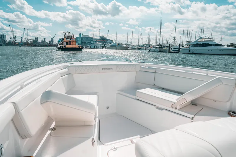Slide: The Image of 2022 Everglades 395cc boat interior with marina view, featuring luxurious white seating. - 26