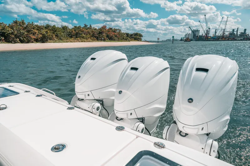 Slide: The Image of Three white outboard motors on a 2022 Everglades 395cc boat, near a scenic shoreline. - 37