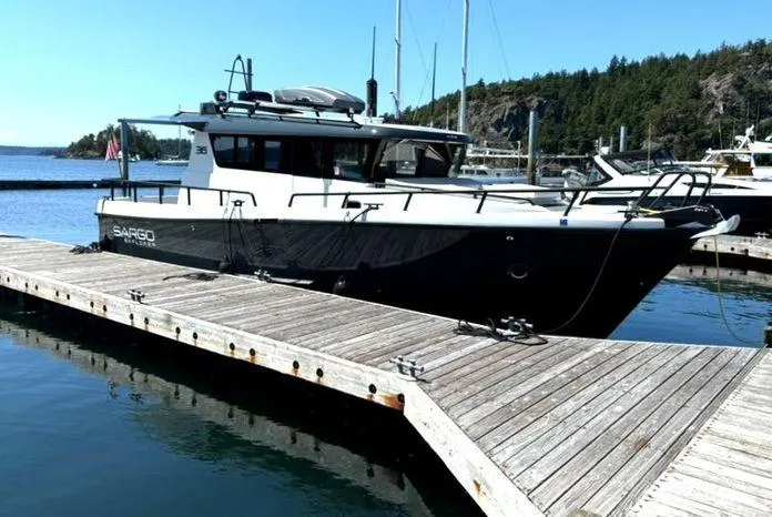 Slide: The Image of 2024 Sargo 36 boat docked at a marina, surrounded by calm water and trees. - 40