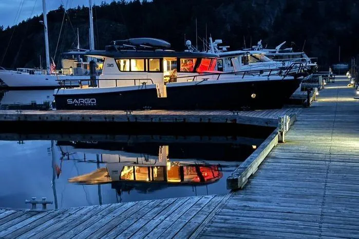Slide: The Image of 2024 Sargo 36 boat docked at marina, reflecting on calm water at dusk. - 41
