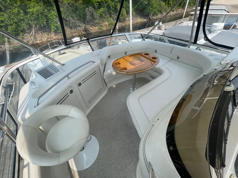 Slide: The Image of 2001 Sea Ray 480 Sedan Bridge yacht interior with white seating and wooden table. - 22