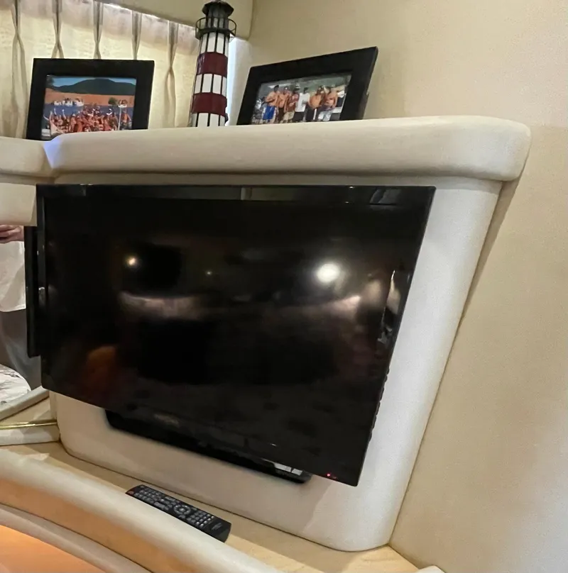 Slide: The Image of Flat-screen TV in 2001 Sea Ray 480 Sedan Bridge interior with framed photos and lighthouse decor. - 44