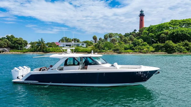 The Image of 2025 Tiara Yachts 48 LS cruising near a lighthouse on a sunny day. - 0