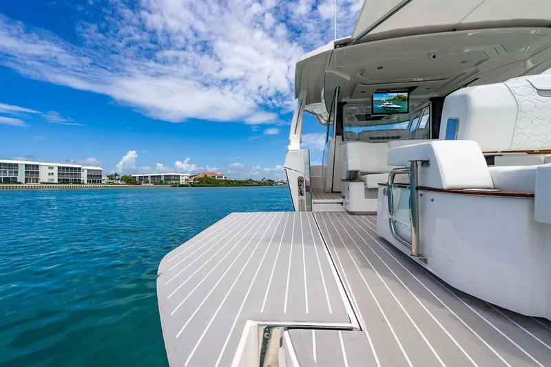 Slide: The Image of 2025 Tiara Yachts 48 LS luxury yacht on serene blue water, featuring elegant deck and seating. - 17