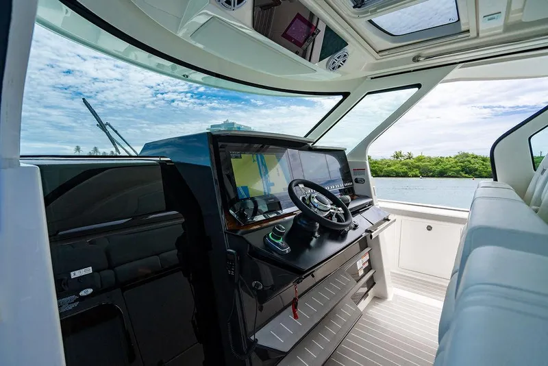 Slide: The Image of Interior view of 2025 Tiara Yachts 48 LS helm with modern controls and scenic water backdrop. - 48
