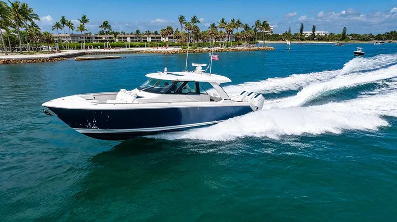Slide: The Image of 2025 Tiara Yachts 48 LS cruising on clear blue water near a tropical shoreline. - 6