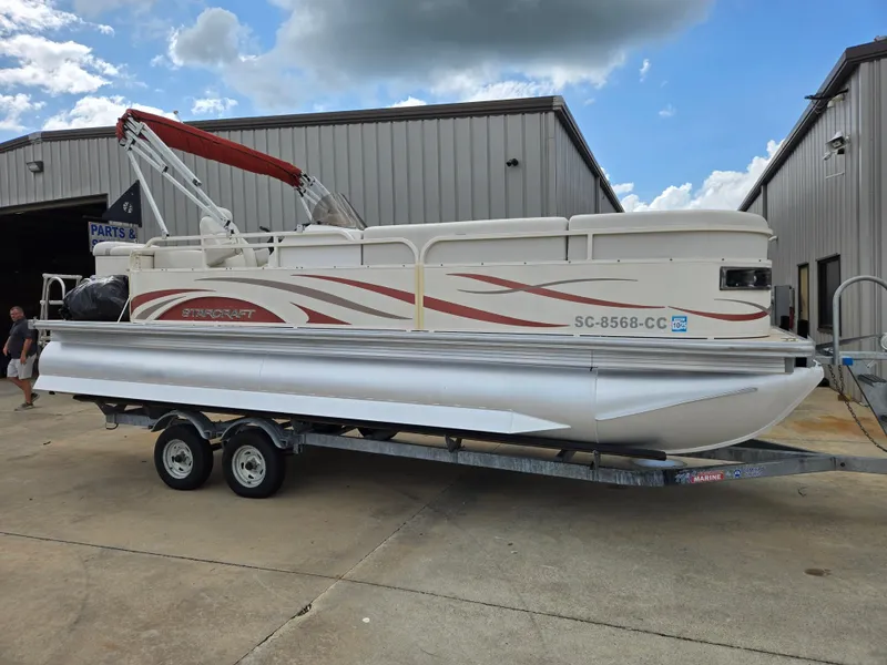 Slide: The Image of 2008 Starcraft Elite 226 RE CR pontoon boat on trailer, parked outside a building. - 0