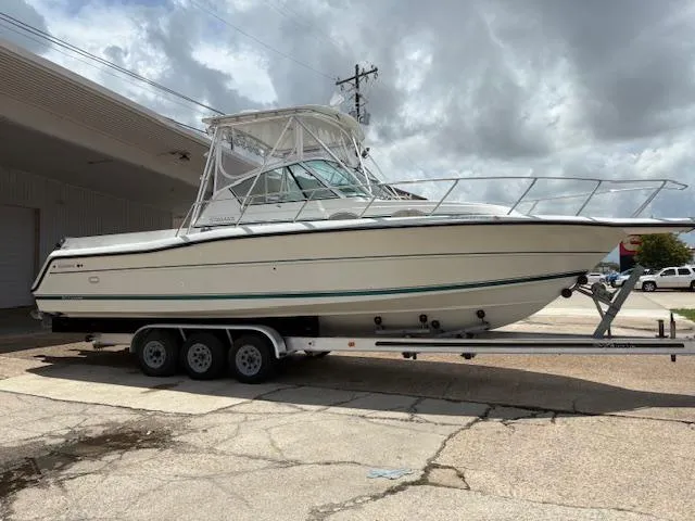 The Image of 1997 Stamas 310 Express boat on a trailer, parked outdoors under cloudy skies. - 1