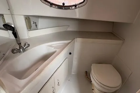 Slide: The Image of 1997 Stamas 310 Express boat bathroom with sink, toilet, and porthole window. - 6