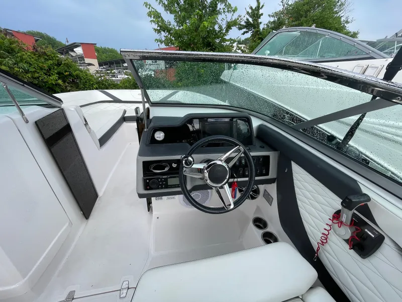 Slide: The Image of 2020 Regal 26 OBX boat interior with steering wheel and dashboard, wet from rain. - 2
