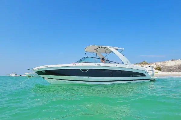 Slide: The Image of 2020 Regal 26 OBX boat anchored in clear turquoise water near a sandy beach. - 8