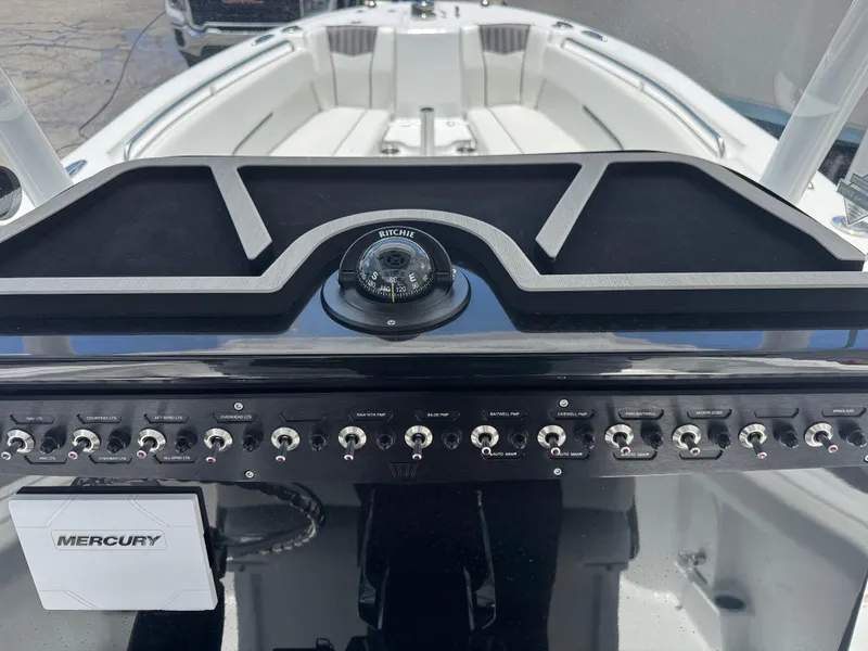 Slide: The Image of 2025 Wellcraft 242 Fisherman dashboard with compass and Mercury controls. - 19