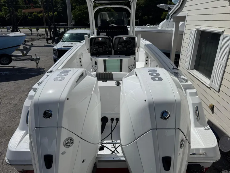 Slide: The Image of 2025 Wellcraft 242 Fisherman boat with dual outboard engines, parked near a building. - 3