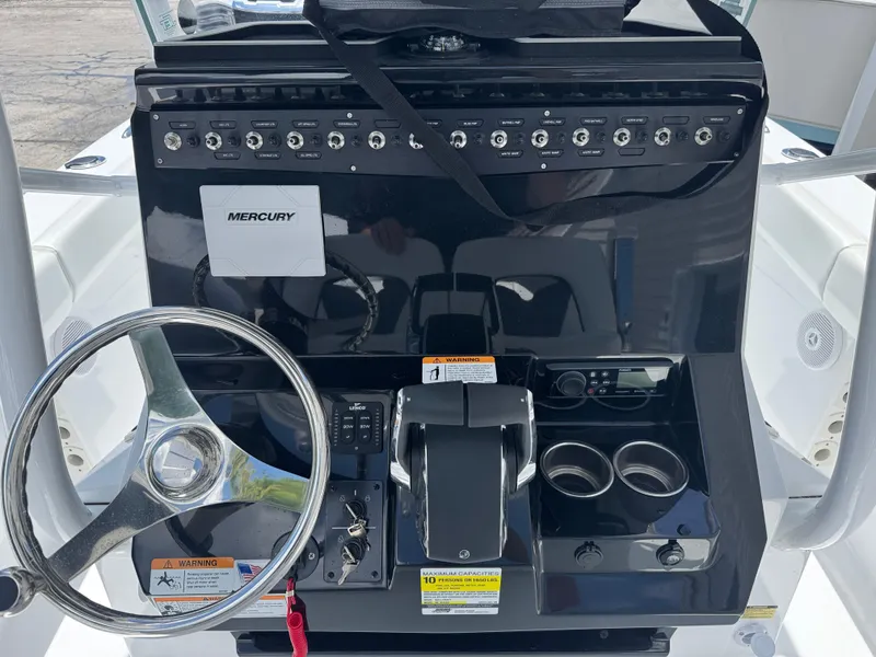 Slide: The Image of 2025 Wellcraft 242 Fisherman boat dashboard with steering wheel and Mercury controls. - 9