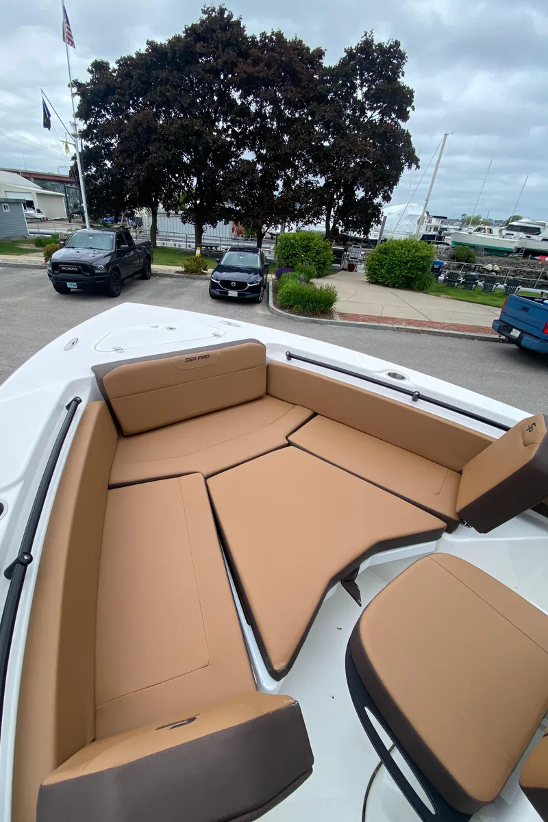 Slide: The Image of 2025 Sea Pro 225 Sandbar boat with tan seating, docked near trees and parked cars. - 12