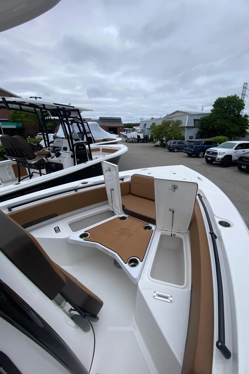 Slide: The Image of 2025 Sea Pro 225 Sandbar boat with open storage compartments, docked in a marina. - 8