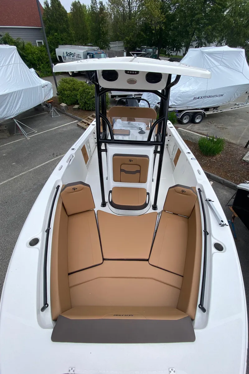 Slide: The Image of 2025 Sea Pro 225 Sandbar boat with tan seating and sleek design, parked outdoors. - 9
