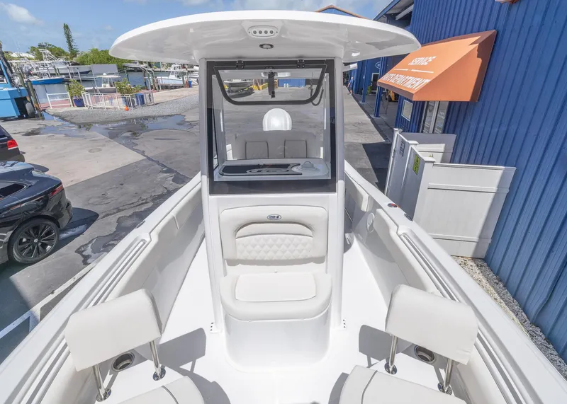 Slide: The Image of 2026 Sea Hunt Ultra 235 SE boat interior with seating and console, docked near blue building. - 3