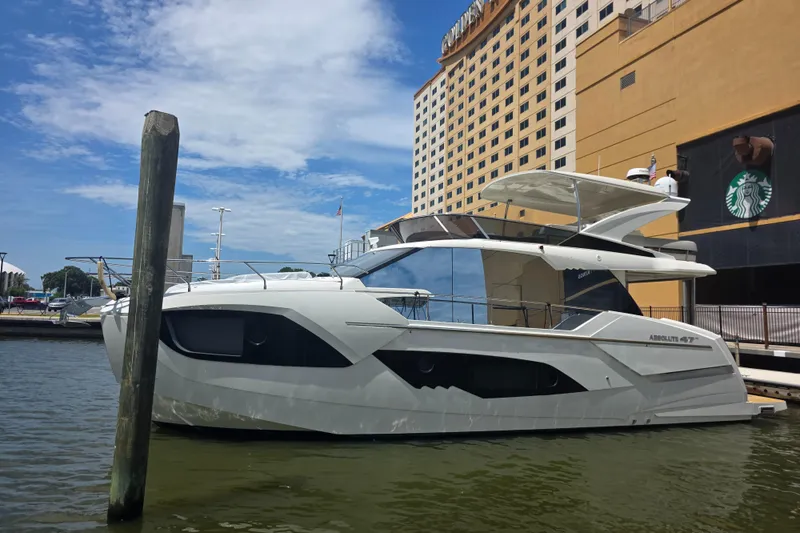 Slide: The Image of 2021 Absolute 47 Fly yacht docked near a tall building under a blue sky. - 6