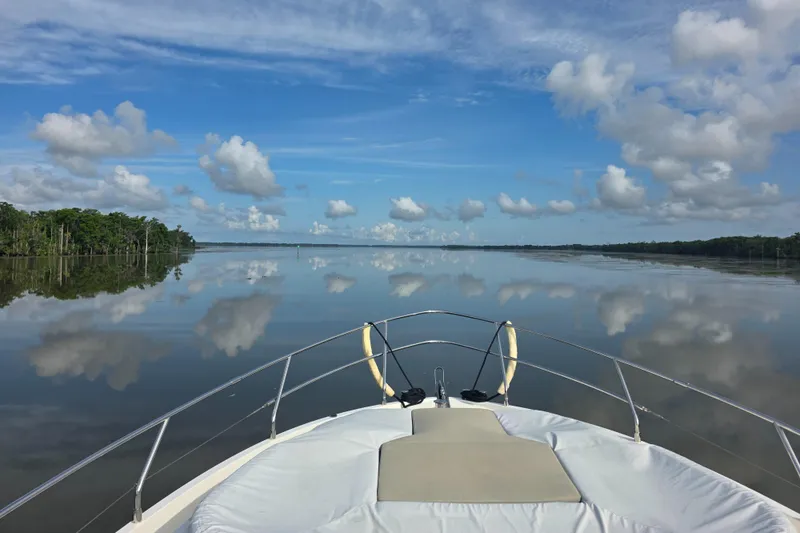 Slide: The Image of Bow of Absolute 47 Fly yacht on calm water, reflecting clouds and blue sky. - 8