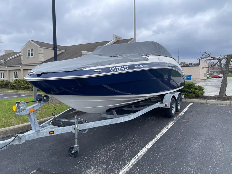 Slide: The Image of 2011 Yamaha Boats 242 Limited on trailer, covered, parked in lot under cloudy sky. - 3