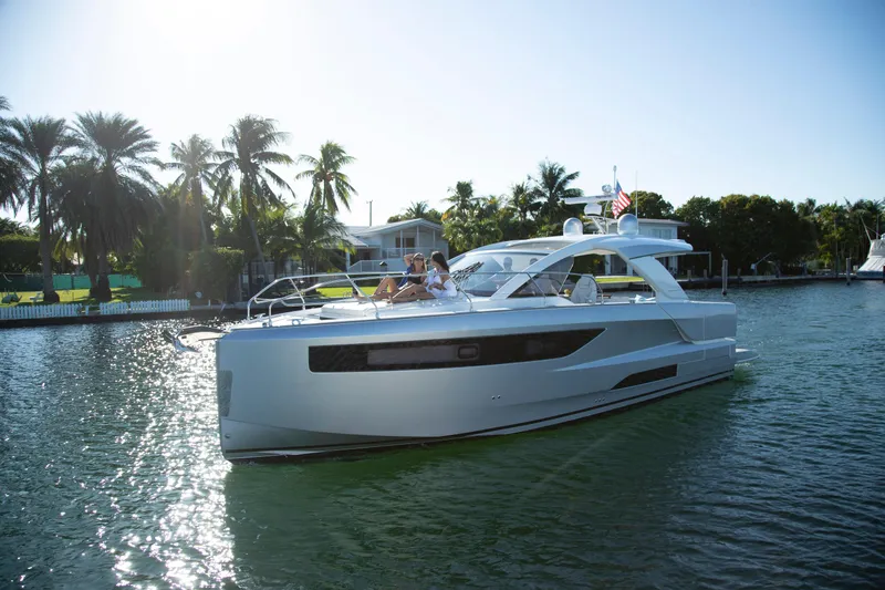 Slide: The Image of 2025 Jeanneau DB 43 yacht cruising on a sunny day with palm trees in the background. - 2