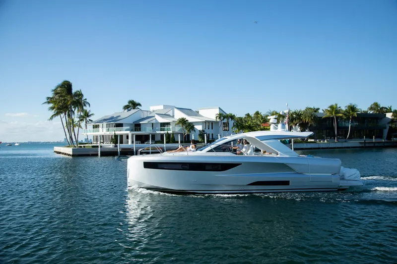 Slide: The Image of 2025 Jeanneau DB 43 yacht cruising near waterfront homes and palm trees. - 4