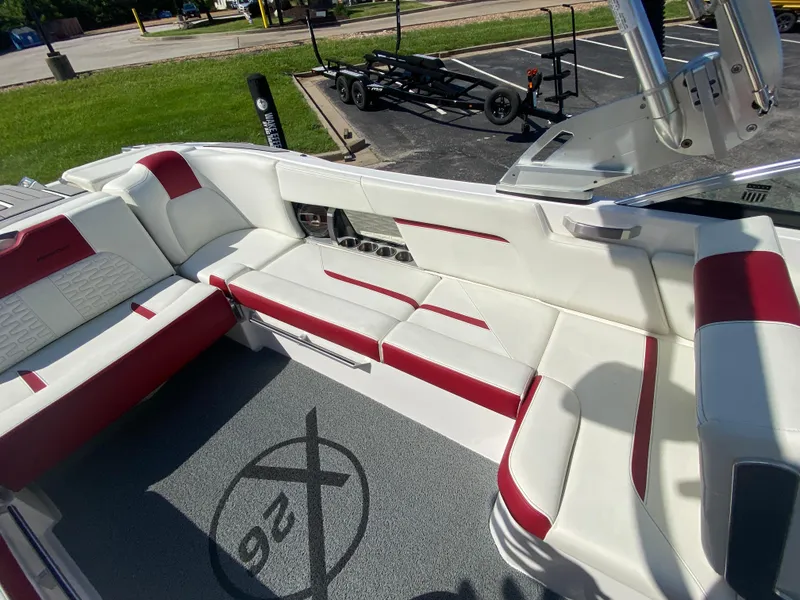 Slide: The Image of 2020 MasterCraft X26 boat interior with white and red seating, parked on pavement. - 19