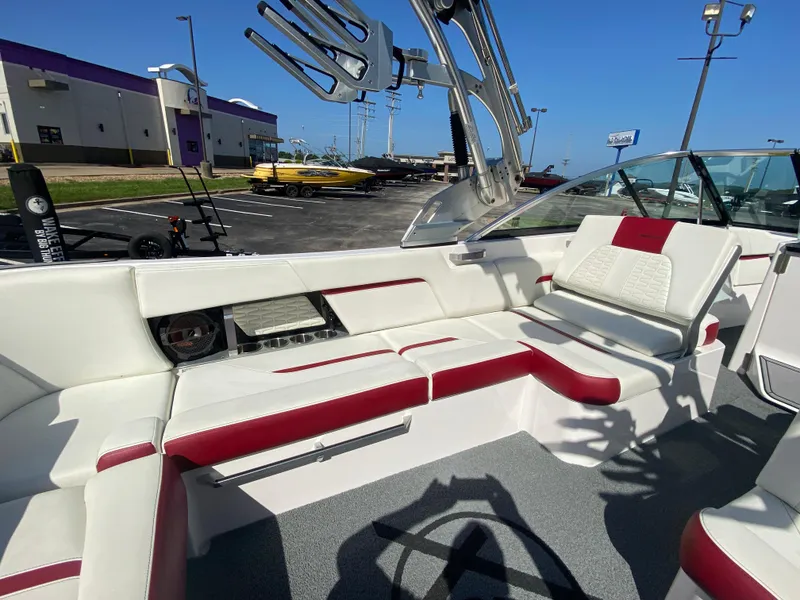Slide: The Image of 2020 MasterCraft X26 boat interior with white and red seating, parked outdoors. - 20