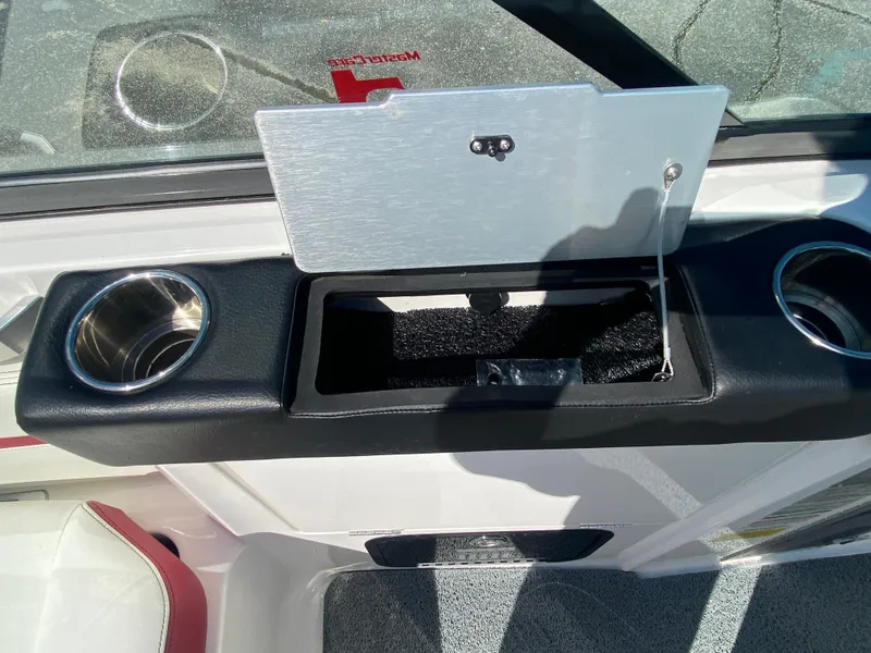 Slide: The Image of 2020 MasterCraft X26 boat interior with open storage compartment and cup holders. - 24