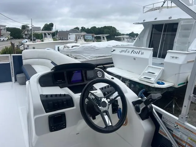 Slide: The Image of 2021 Hurricane FunDeck 236SB OB boat interior with steering wheel and docked boats in background. - 5