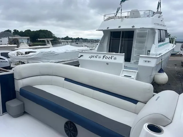 Slide: The Image of 2021 Hurricane FunDeck 236SB OB with white seating, docked near a yacht named "April's Fool's." - 7