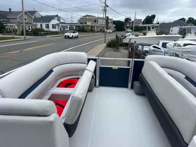 Slide: The Image of 2021 Hurricane FunDeck 236SB OB boat interior with seating and life jackets, parked near a street. - 9