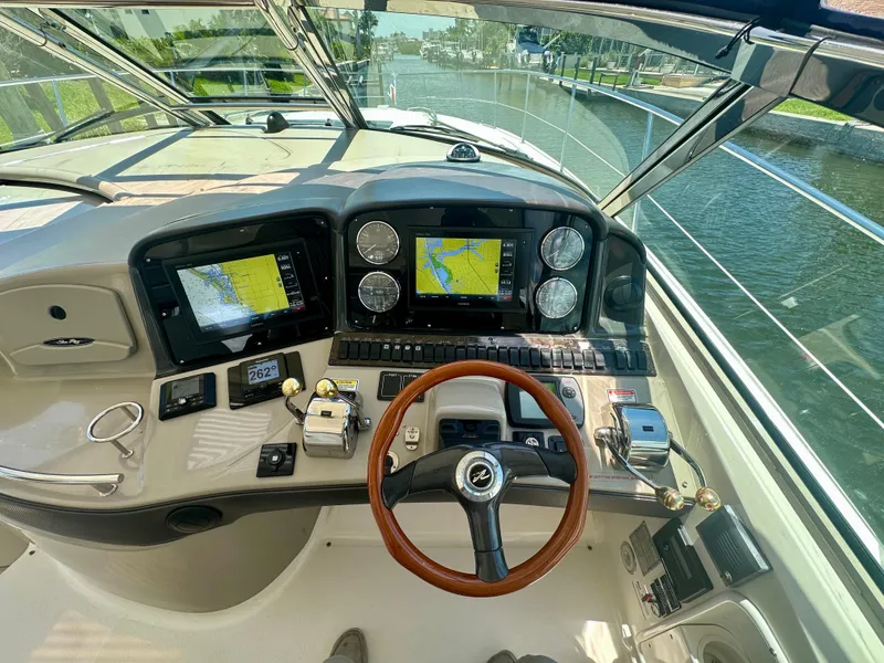 Slide: The Image of 2005 Sea Ray 420 Sundancer helm with navigation screens and controls, docked by a canal. - 12