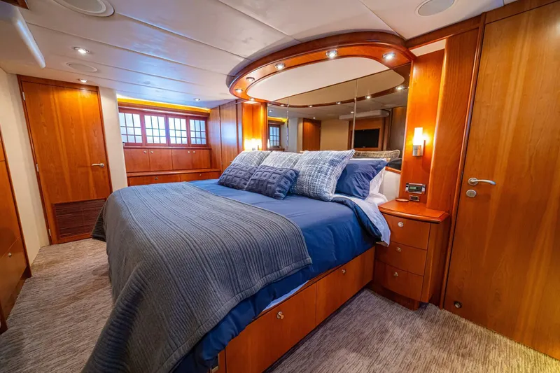 Slide: The Image of Luxurious bedroom interior on 2002 Queenship 98 Yachtfish, featuring elegant wood finishes and plush bedding. - 29