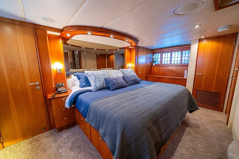 Slide: The Image of Luxurious bedroom on 2002 Queenship 98 Yachtfish, featuring elegant wood paneling and plush bedding. - 30