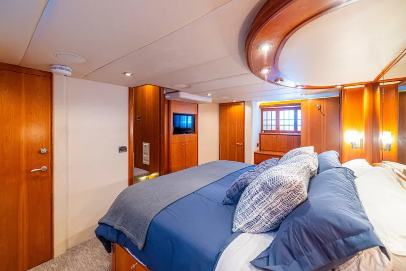 Slide: The Image of Luxurious bedroom interior of 2002 Queenship 98 Yachtfish, featuring elegant wood finishes and cozy bedding. - 33