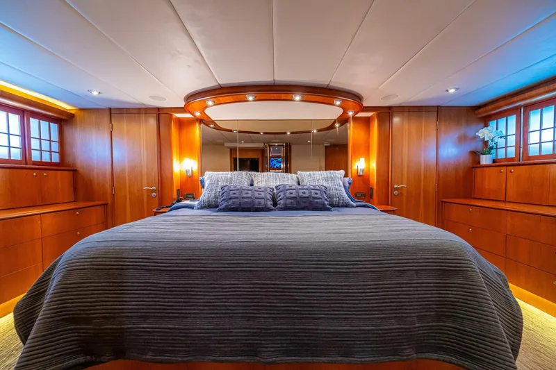 Slide: The Image of Luxurious bedroom interior of 2002 Queenship 98 Yachtfish, featuring elegant wood paneling and plush bedding. - 4