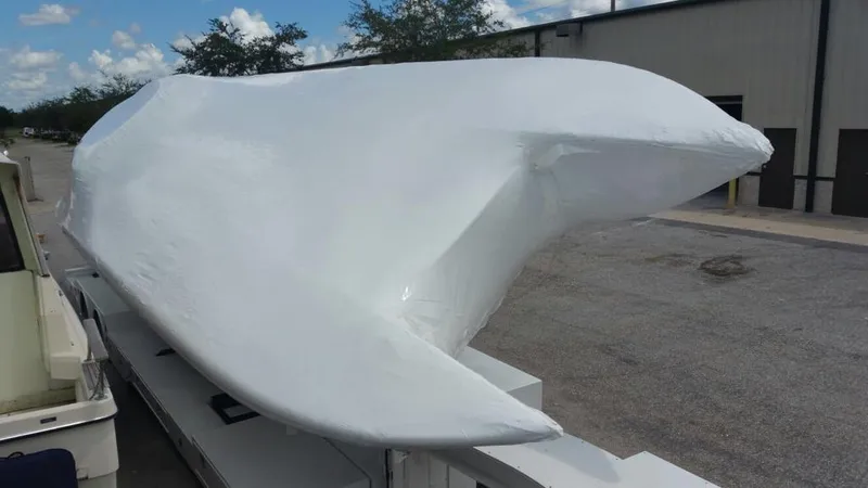 Slide: The Image of 2012 Mystic Powerboats 50 Cat covered in white protective wrap, parked outdoors. - 9