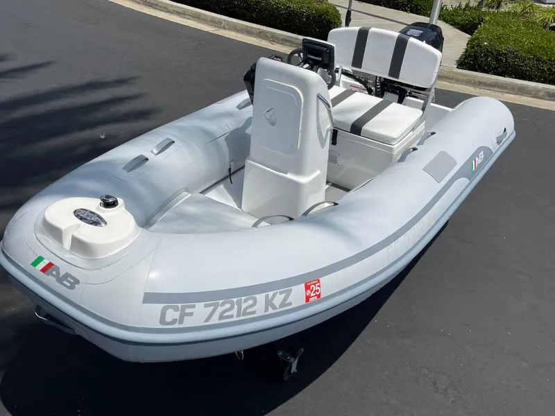 Slide: The Image of 2013 AB Inflatables Lammina 10 AL boat, gray with seating and console, parked on pavement. - 18